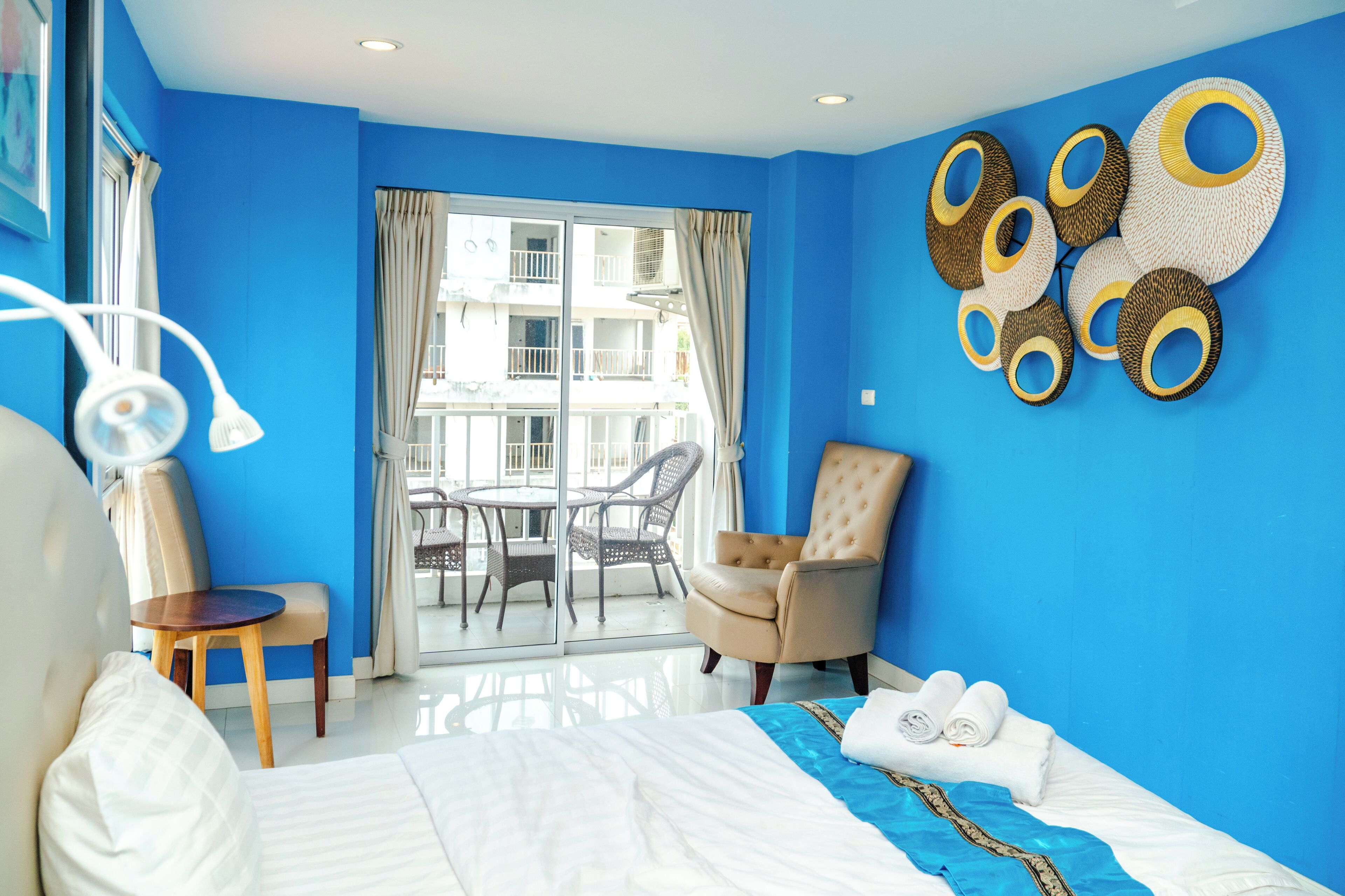 Habitación de hotel con una cama grande, una silla, una mesita y un balcón con vistas al edificio.