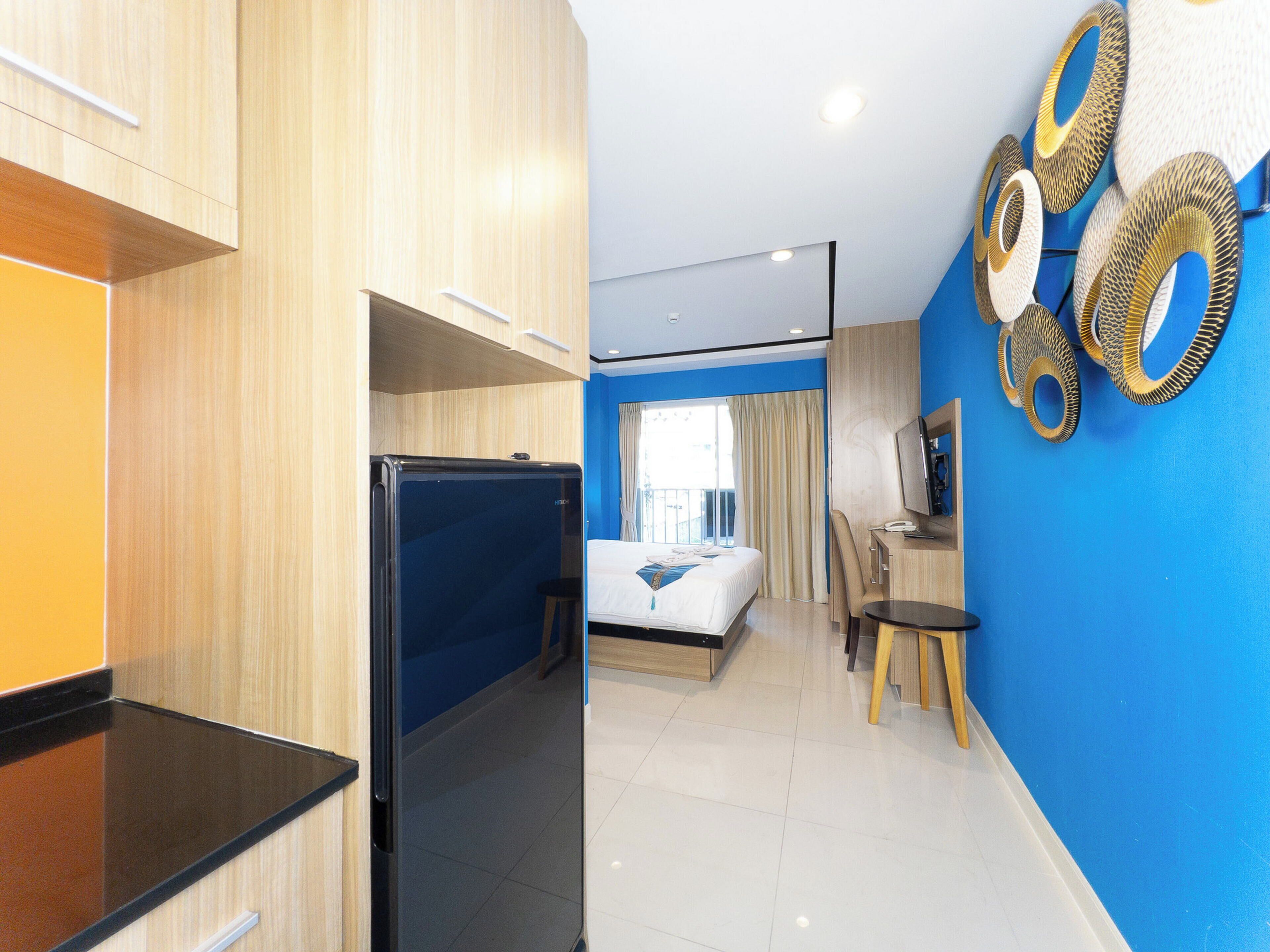 Une chambre d’hôtel équipée d’un lit, d’un bureau, d’une chaise, d’une télévision et d’un mini-bar.
