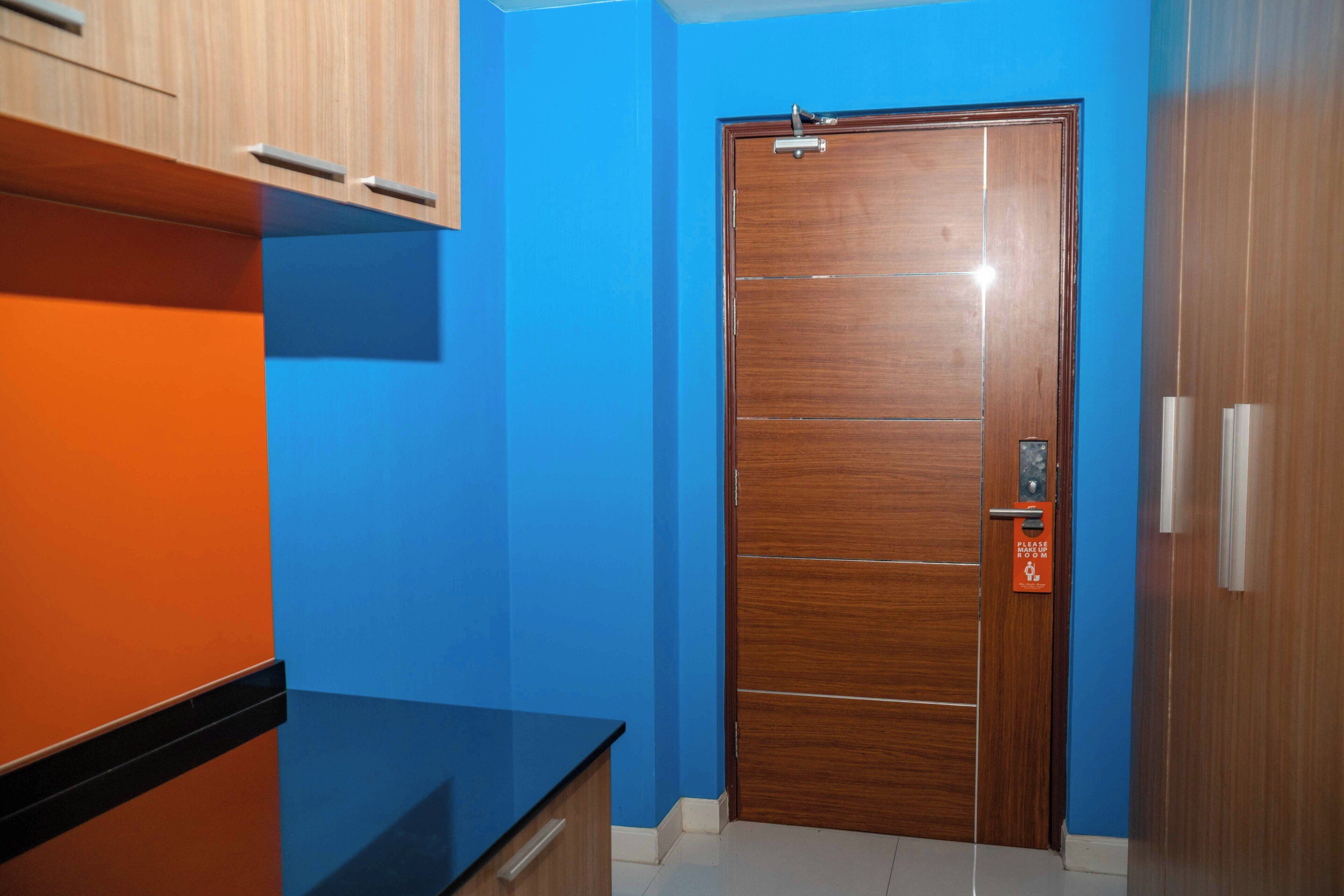 Een kamer met een houten deur, een blauwe wand en een zwart aanrecht.