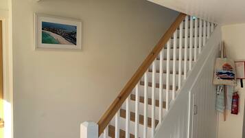 A staircase with white railings and wooden steps, a framed picture on the wall, and a fire extinguisher on the right.