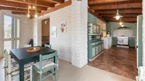 A rustic kitchen with a stone wall, wooden beams, and a dining area with a table and chairs. - Villa Scrusciu Ri Mari with private pool, Noto (Sicilia)