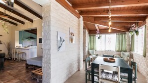 A rustic dining area with a wooden table and chairs, a stone wall, and a kitchen in the background. - Villa Scrusciu Ri Mari with private pool, Noto (Sicilia)