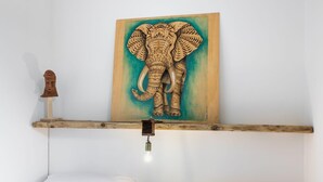 A room with a wooden shelf displaying a carved elephant artwork, a small wooden figure, and a hanging light fixture. - Villa Scrusciu Ri Mari with private pool, Noto (Sicilia)