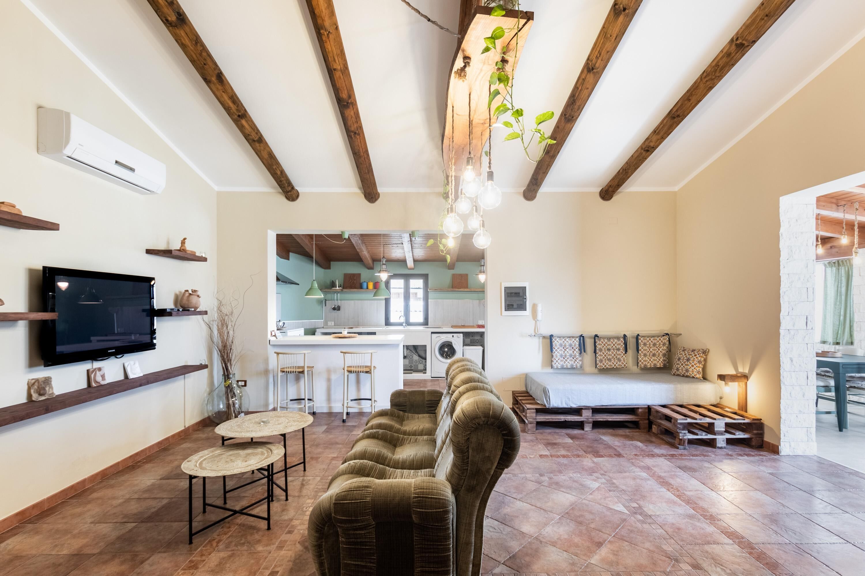 A cozy living room with a sofa, a TV, and a kitchen in the background.