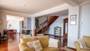 Un vaste salon doté d’un escalier en bois, d’un coin repas et d’une cheminée.