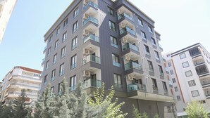 A multi-story residential building with balconies, air conditioning units, and a modern architectural design.