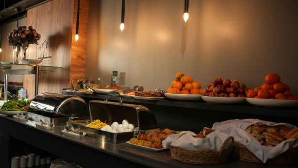 A buffet with various food items including fruits, pastries, and a salad.