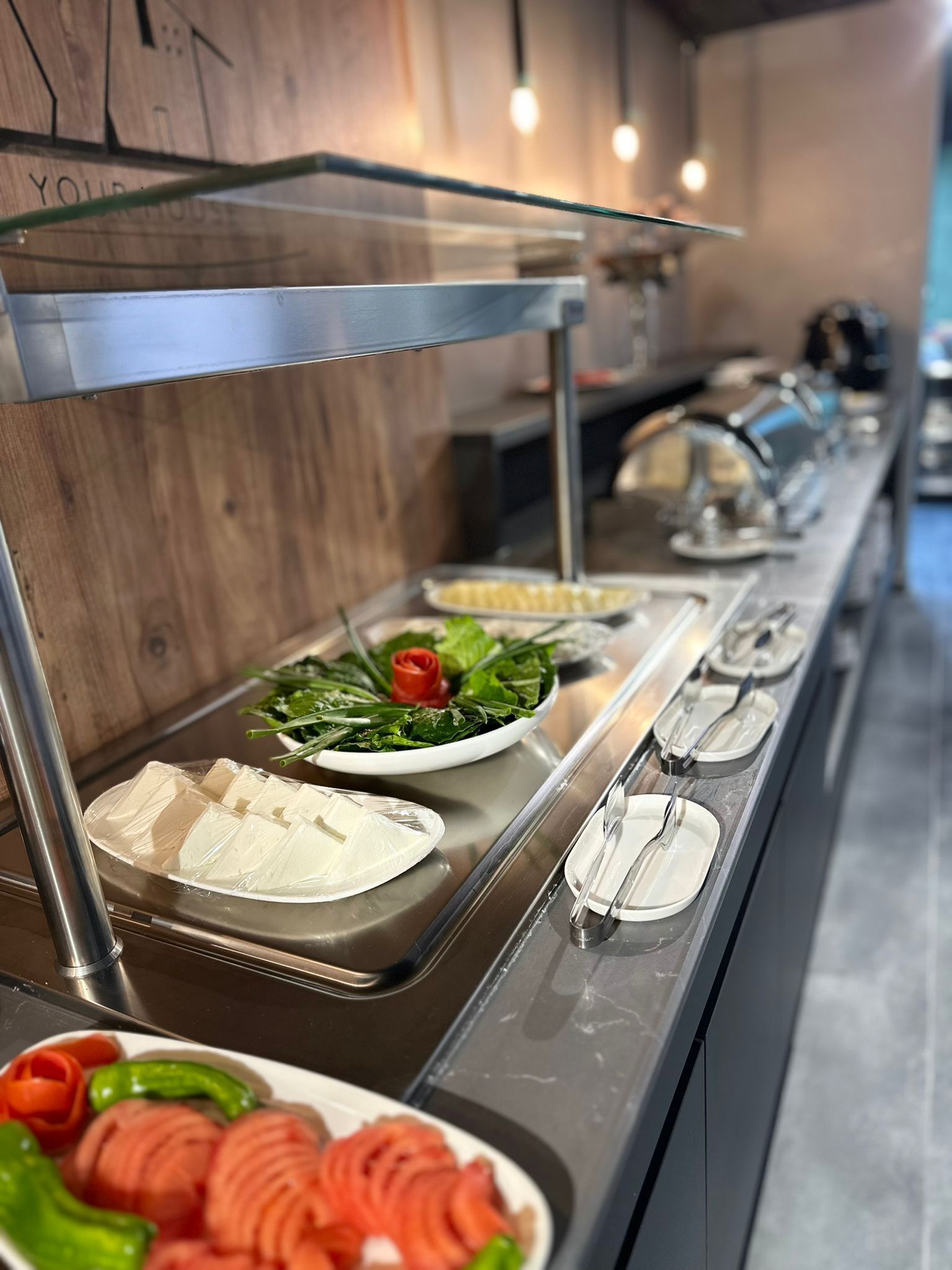 A buffet setup with various food items including tofu, vegetables, and sliced meats.