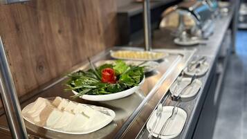 A buffet setup with various food items including tofu, vegetables, and sliced meats.