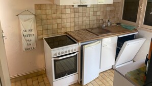 A compact kitchen with white cabinets, a built-in oven, a dishwasher, and a sink. - Mountain chalet   (Mont-Dore)