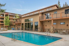 A hotel with a swimming pool, outdoor seating, and a stone facade. - Terracehouse 52 (Snowmass Village)