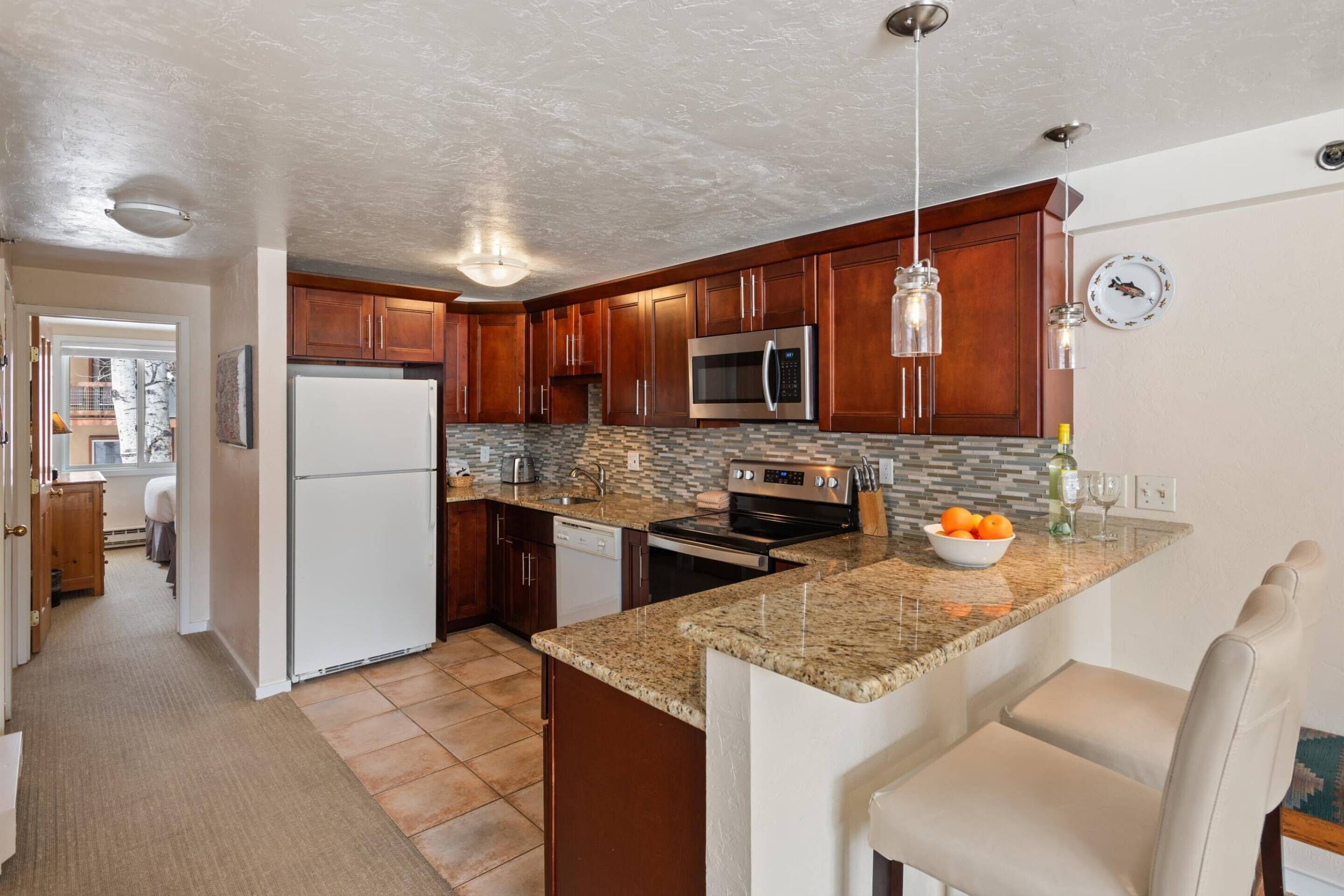 A modern kitchen with granite countertops, stainless steel appliances, and wooden cabinets.
