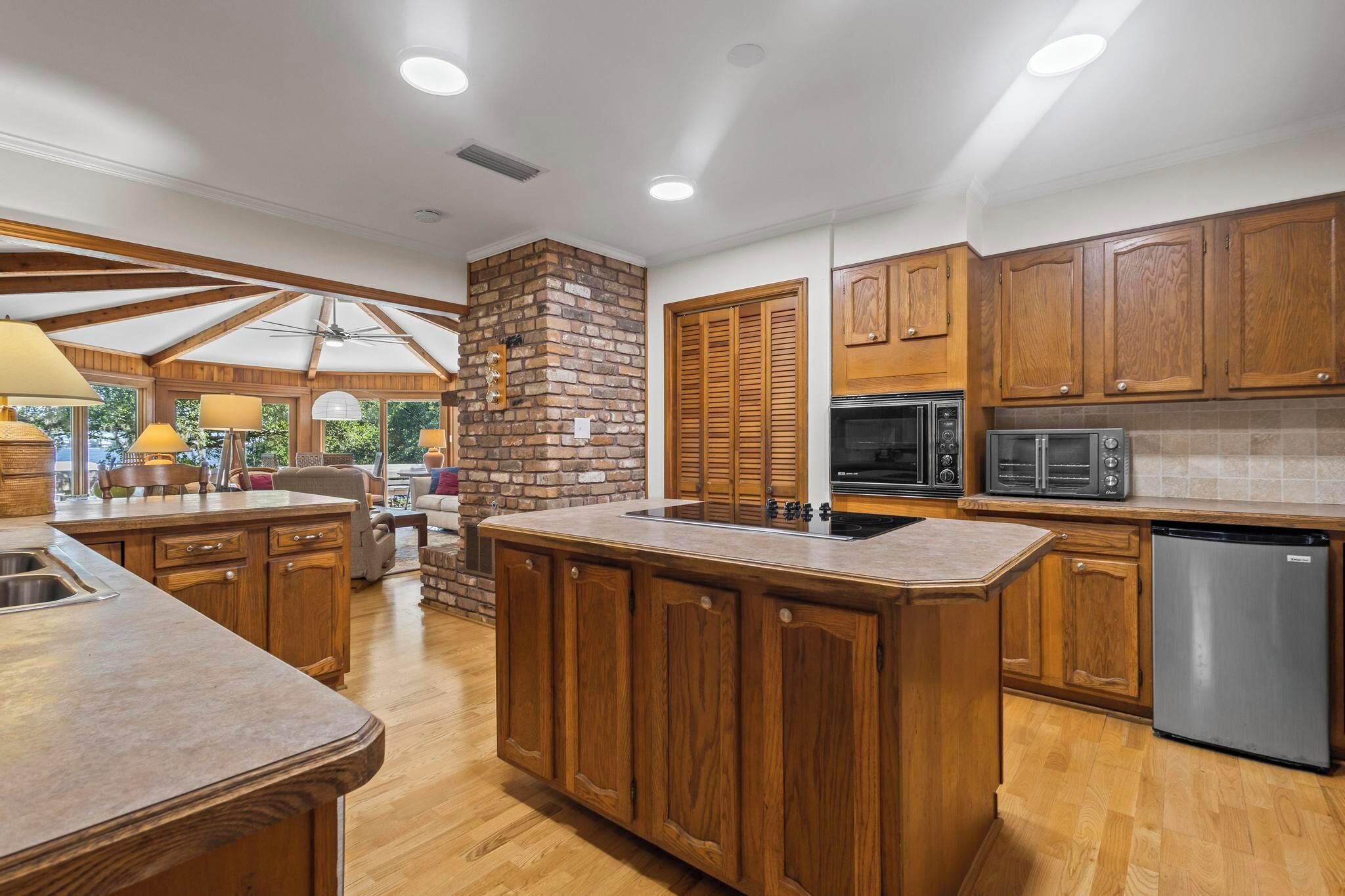 Una cocina con armarios de madera, pared decorada con ladrillo y electrodomésticos modernos.