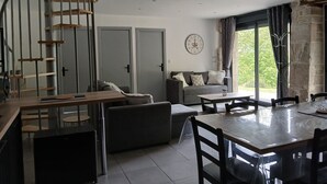 Un interior moderno con una escalera, un comedor, un sofá y vistas a través de una ventana.