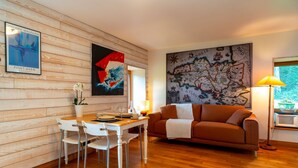A dining area with a wooden wall, a map, and a brown sofa. - Le Relais - Maison avec grand jardin (Bannalec)