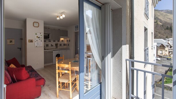 En moderne lejlighed med spiseplads, køkken og balkon med udsigt over kvarteret.