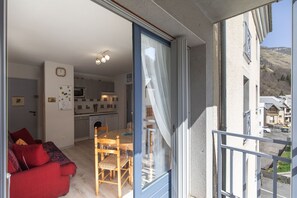 A modern apartment with a dining area, kitchen, and a balcony with a view of the neighborhood.