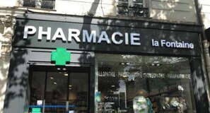 A pharmacy with a green cross sign above the entrance. - The watercolor- Family & Sophisticated -Auteuil (Paris)