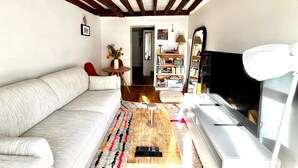 Un salon avec un canapé, une table basse, un téléviseur et une bibliothèque.