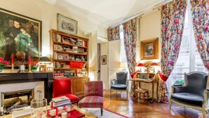 Un salon chaleureux avec une cheminée, une bibliothèque et un coin salon confortable.