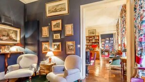 Une pièce avec deux fauteuils, une moquette verte et une bibliothèque remplie de livres.