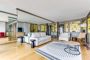 Un salon moderne comprenant un canapé, des fauteuils, une table basse et une bibliothèque remplie de livres.