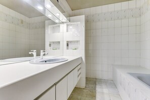 Un baño moderno con dos lavamanos, un espejo grande y una bañera.
