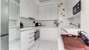 Een moderne keuken met witte kasten, een ingebouwde oven, een koffiezetapparaat en een magnetron.