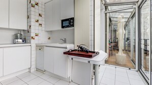 Een moderne keuken met witte kasten, een magnetron, een vaatwasser en een raam met uitzicht.