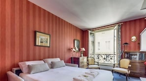 Een hotelkamer met een groot bed, een dressoir, een stoel en een raam met uitzicht.
