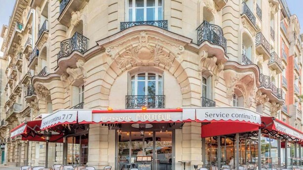 A historic building with ornate architecture, a red awning, and outdoor seating. - The architect - Design & Luxurious (Paris)