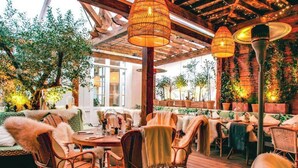 An outdoor restaurant with wicker furniture, hanging lamps, and potted plants. - The architect - Design & Luxurious (Paris)