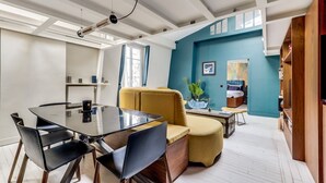 A modern living room with a glass-top dining table, comfortable seating, and a blue accent wall. - The architect - Design & Luxurious (Paris)