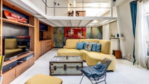 A modern living room with a sofa, a coffee table, a television, and a painting on the wall. - The architect - Design & Luxurious (Paris)