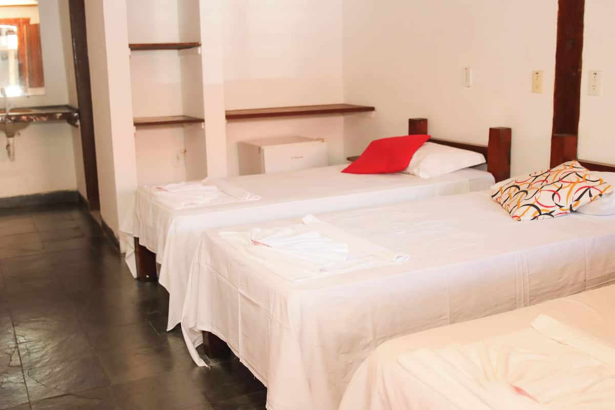 A hotel room with two single beds, a wooden headboard, a small bedside table, and a wardrobe with a mirror.