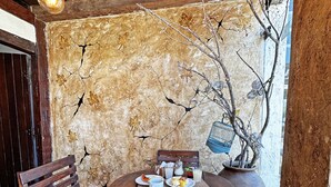 A rustic dining area with a wooden table and benches, a rustic wall with a tree branch, and a hanging light fixture. - POUSADA LUZ DO SOL (Porto Seguro)