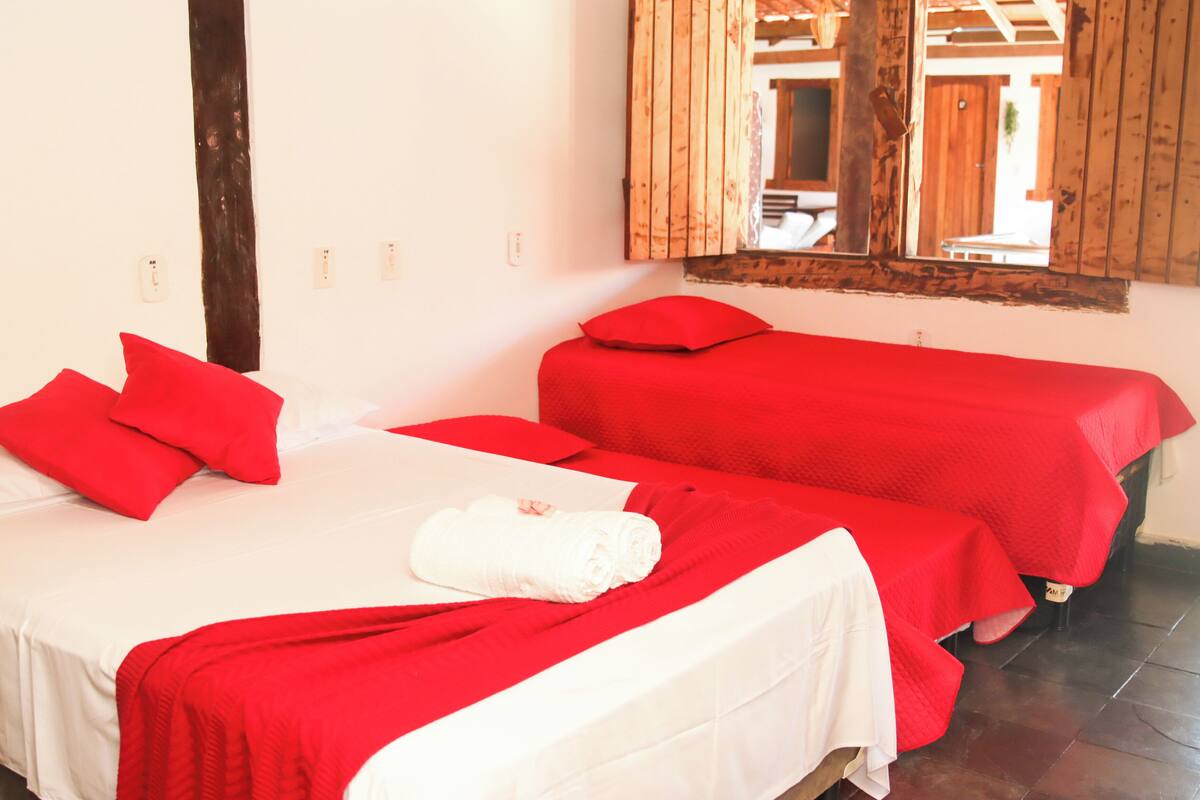 A room with two beds, each with red bedding and pillows, and a white towel on one bed.