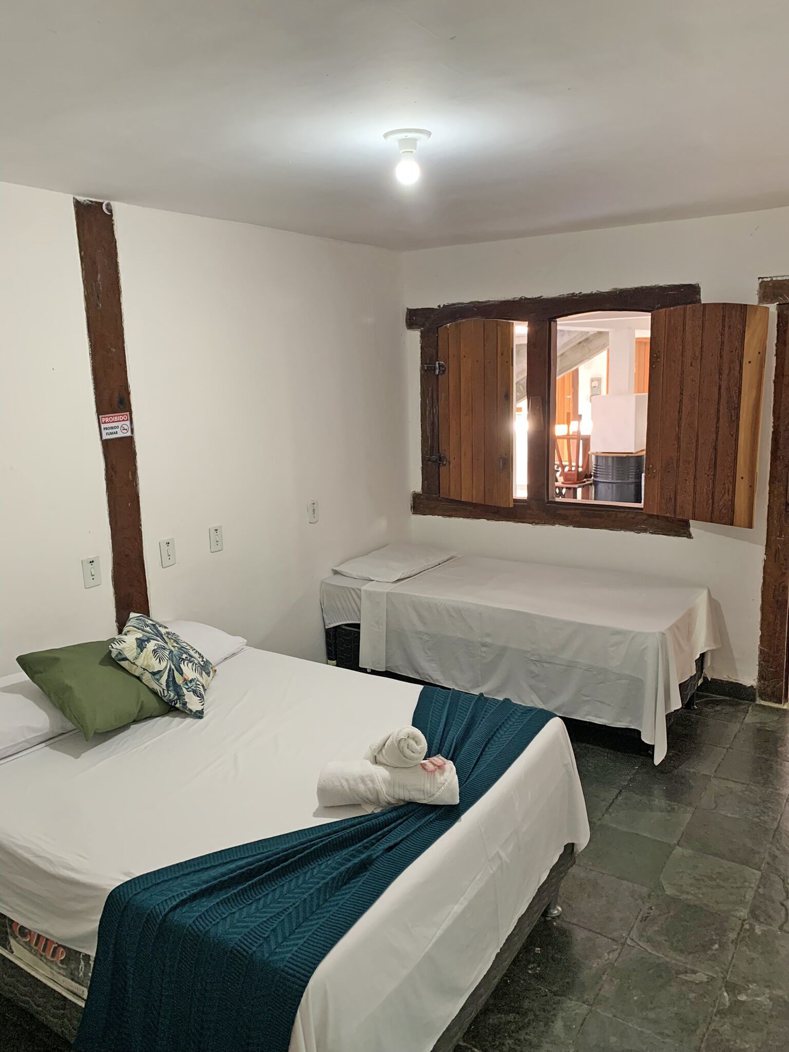 Ein Zimmer mit zwei Betten, einer Holztür und einem kleinen Fenster.