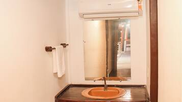 Un baño con un tocador de madera, un lavabo y un espejo.