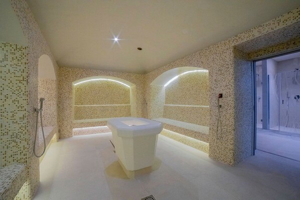 Un baño moderno con una bañera independiente, paredes de mosaico y un box de ducha de vidrio.