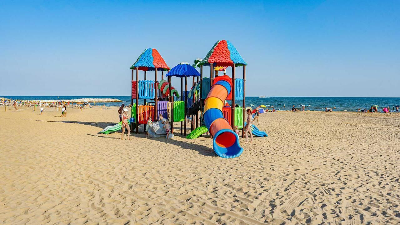 Una playa con una estructura de juegos colorida y un tobogán.