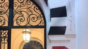 A hotel entrance with a wrought iron gate, a lit lamp above the door, and a sign reading "TRANSATLANTIQUE". - Hotel Transatlantique (Tunis)