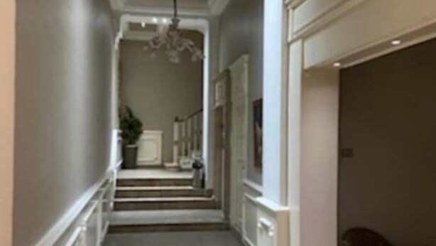 A hallway with a chandelier, a staircase, and a chair. - Hotel Transatlantique (Tunis)