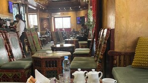 A dining area with traditional wooden furniture, a table set with plates, cups, and a jug of orange juice. - Hotel Transatlantique (Tunis)