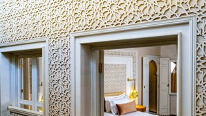 A room with intricate white wall carvings, a bed with a white headboard, and a small table with a lamp. - Riad Glatt K: a Luxurious Oasis in the Heart of Marrakech. (Marrakech)