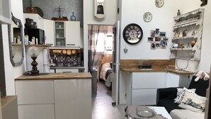 A compact kitchen with a central island, a dining area with a bench, and a living space with a sofa and a coffee table. - Joli Petit Mazet Avec Terrasse en Pleine Nature (COGOLIN)