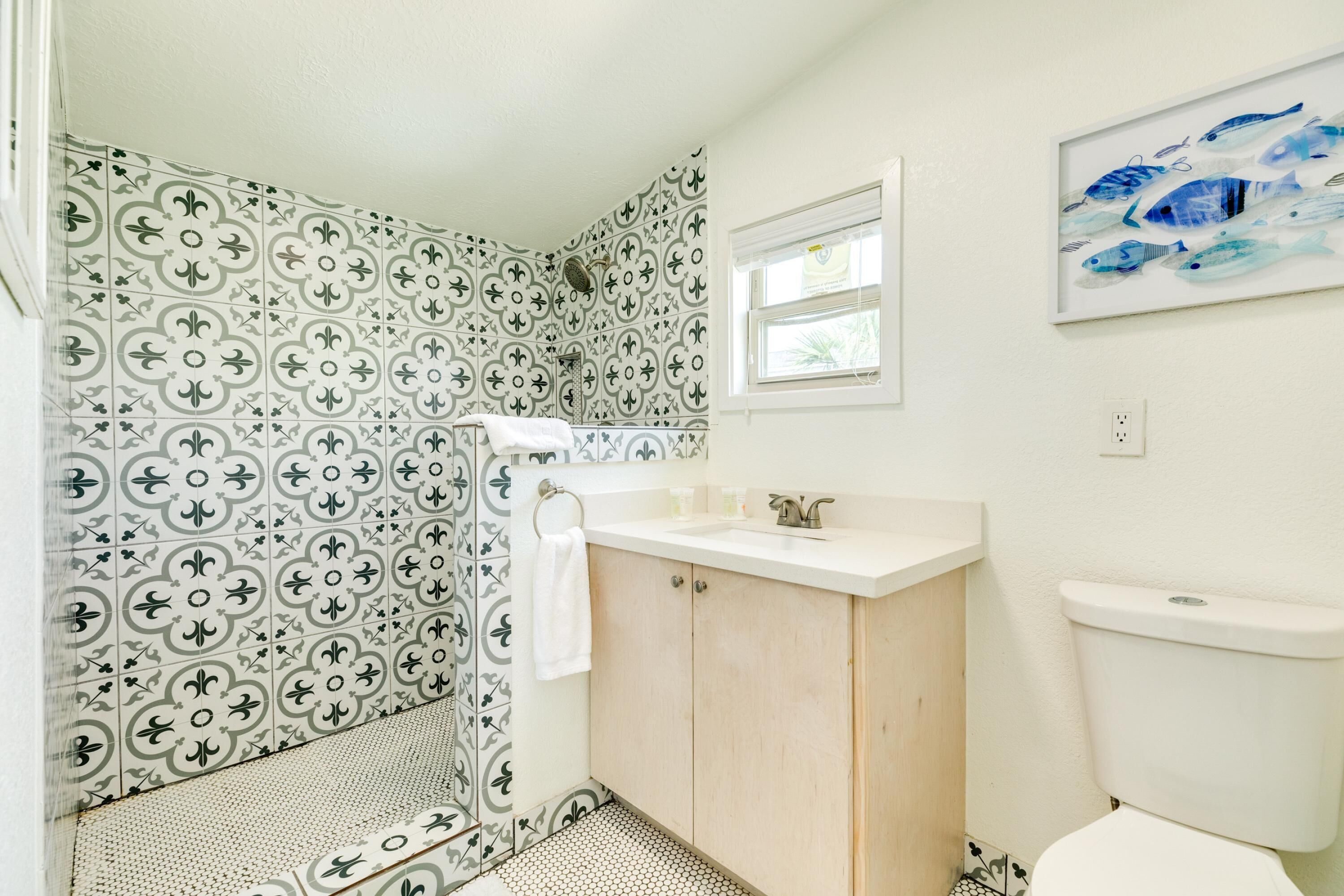 Een badkamer met patroontegels, een witte wastafel, houten kastjes en een toilet.
