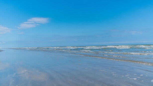 A beach with clear skies and calm waves. - Cute Beach Bungalow Walk to the Beach (Galveston)