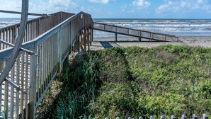 Une promenade en bois menant à une plage, avec un ciel dégagé.