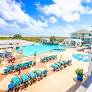 A pool area with multiple lounge chairs and a large pool.
